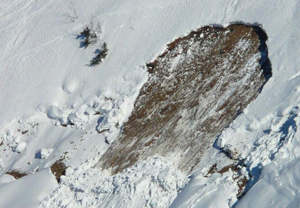 Aftermath of an snow avalanche on the side of a mountain.