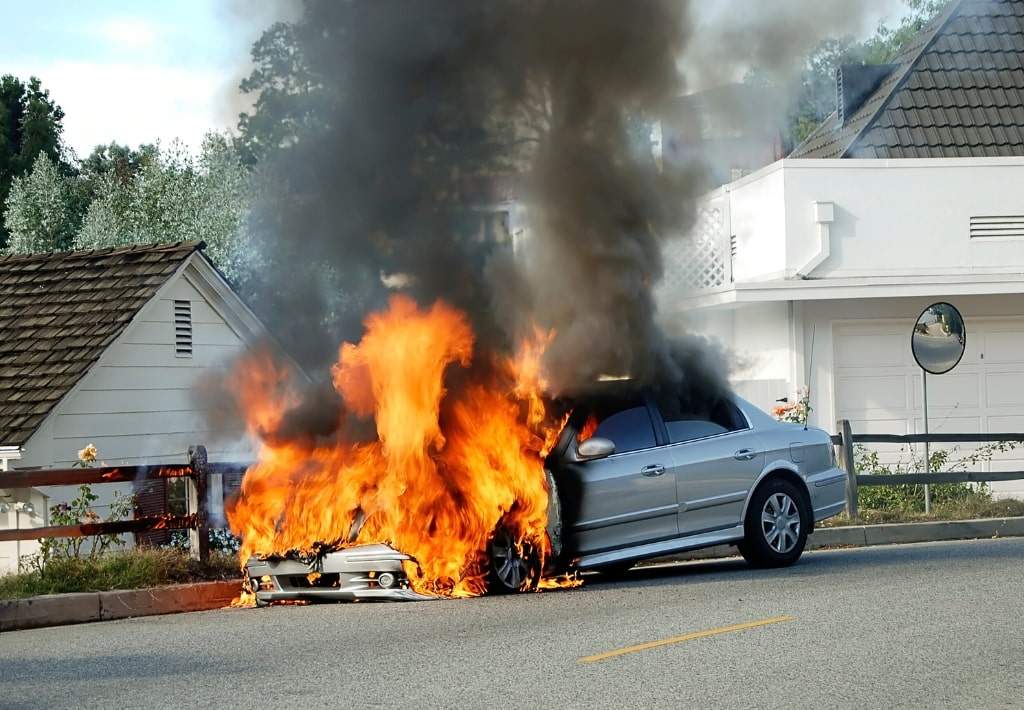 Vehicle on fire on the side of the road.