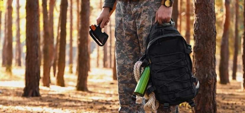 Man holding a bug-out-bag in the woods.